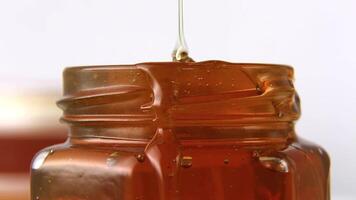 The honey a stream of golden honey flows into a jar. video