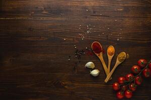 Various Asian spices in wooden spoons on wooden background. Top view photo