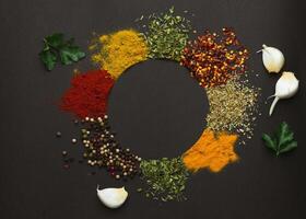 Circle frame composition of spices and herbs isolated on dark background with copy space. Frame of Indian spices and herbs. Ingredients of asian cuisine spices photo