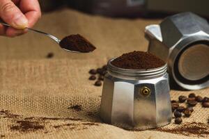 Hands holding roasted coffee beans on burlap and coffee background. Focus on beans. Close up. photo