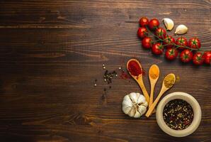 Various Asian spices in wooden spoons on wooden background. Top view photo