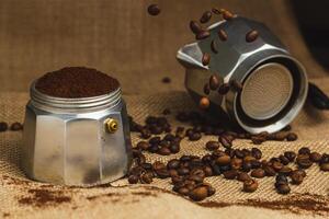 Moka pot and coffee grinder on natural burlap dark background. Coffee making concept. photo