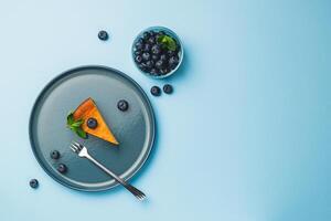 Cottage cheese cheesecake slice with fresh blueberry and mint on blue background, top view photo