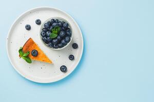 Cottage cheese cheesecake slice with fresh blueberry and mint on blue background, top view photo
