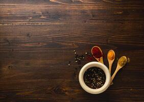 Various Asian spices in wooden spoons on wooden background. Top view photo