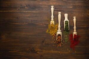 Set of Indian spices in wooden spoons on wooden table. Top view. Copy space photo