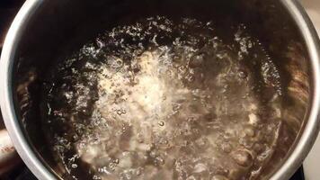 koken water met stoom- stijgende lijn en bubbels vormen in een roestvrij staal pot video