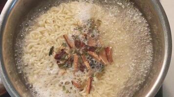 Boiling instant noodles with spices in a pot on the stove in the kitchen video