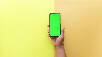topo Visão do mão segurando uma inteligente telefone com verde tela em cor fundo video