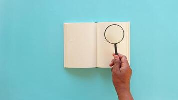 holding a magnifying glass searching something on book video