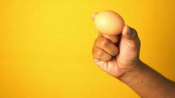 close up of men hand holding a egg against orange color background video