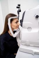 Female patient is checking the eye vision in ophthalmology modern clinic. Woman in ophthalmology clinic. View from the side. Closeup. photo