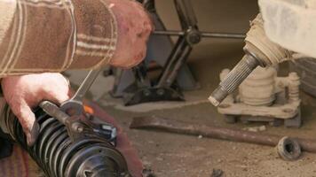 The calloused hands of a mechanic twist the coil spring ties with a wrench during DIY car repairs. video