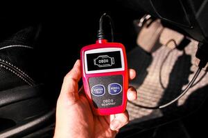 OBD scanner tool , OBD2 scanner in a car mechanic hand for car engine system analysis , Car maintenance and servicing concept photo