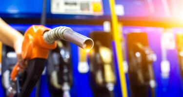 Petrol fuel nozzle in a hand for fuelling in petrol fuel station , horizontal banner with copy space , Fuel and energy concept photo