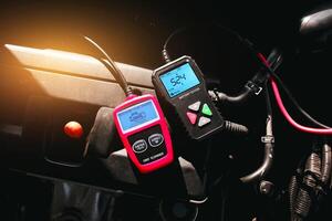 Battery tester and OBD or OBD2 scanner on engine compartment , Car maintenance service concept photo