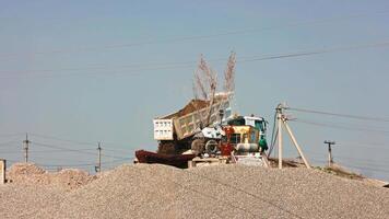 dump truck unloading brown earth with small rocks into intake bunker of asphalt plant video