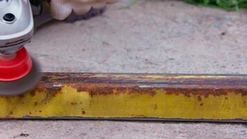 yellow rusted square steel pipe is being cleaned with angle grinder and wire brush video