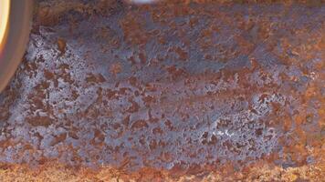 rusted metal surface is being cleaned with angle grinder and a flap disc, full-frame closeup video