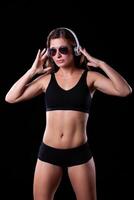 Sporty female girl showing off her perfect body on black background photo