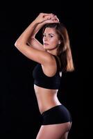 Sporty female girl showing off her perfect body on black background photo