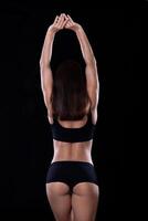 Fitness girl raised her hands on a dark background photo