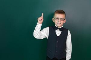 Happy cute clever boy with a bow tie and in glasses had an idea. First time to school. Back to school. photo