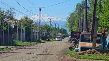 Old trucks and occasional traffic on rural Kyrgyzstan road in Gavrilovka village near Bishkek, Kyrgyzstan video