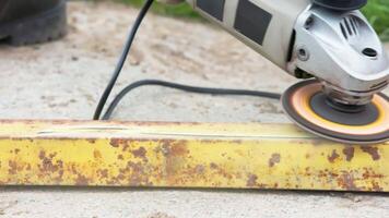 yellow rusted square steel pipe is being cleaned with angle grinder and flap disc video