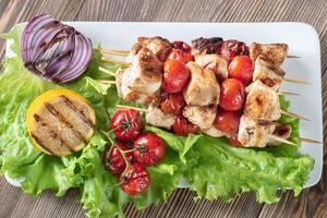 Grilled chicken skewers on the white plate photo