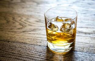 Glass of rum on the wooden background photo