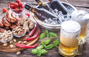 Grilled sausages with appetizers and mugs of beer photo