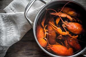 Pot with boiled crayfish on the wooden table photo