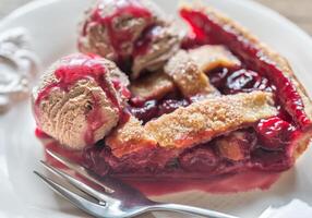 Slice of cherry pie with balls of chocolate ice cream photo