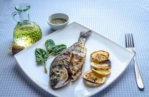 Grilled dorada fish with lemon and spinach photo