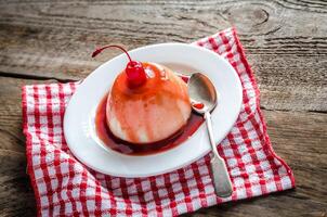 Panna cotta with berry sauce and maraschino cherry photo