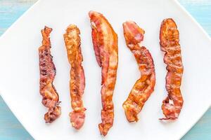 Fried bacon strips on the square plate photo