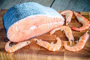 Raw salmon and shrimps on the wooden board photo