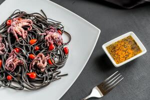 Pasta with black cuttlefish ink and small octopuses photo