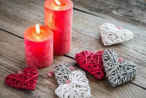 Hearts with burning candles on the wooden background photo