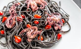Pasta with black cuttlefish ink and small octopuses photo
