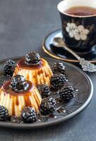 Vanilla puddings with fresh blackberries and berry topping photo