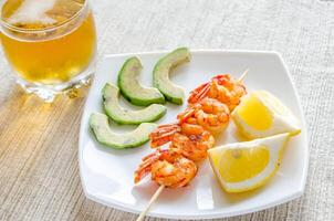 Shrimps skewers with avocado and lemon slices photo