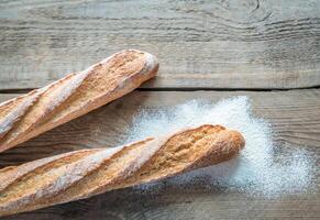 Two wholewheat baguettes on the wooden background photo