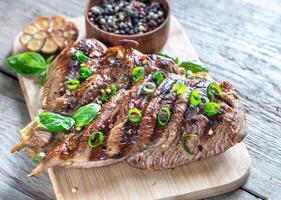Grilled turkey with green scallion on the wooden board photo