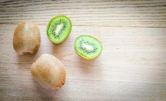 Kiwi on the wooden background whole fruit and cross section photo