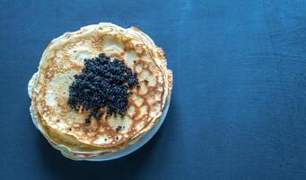 Pile of crepes with black caviar photo
