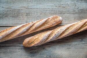 Two wholewheat baguettes on the wooden background photo