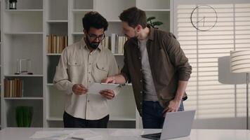 Two diverse businessmen colleagues coworkers business partners work together read data paperwork at office happy joyful Caucasian Indian Arabian men give high five gesture achieve good result teamwork video