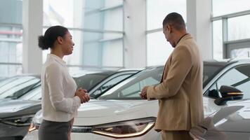 African American woman seller dealer sale automobile credit purchase at dealership salon saleswoman give car key to happy buyer man rent buy new luxury crossover check modern electric auto signaling video